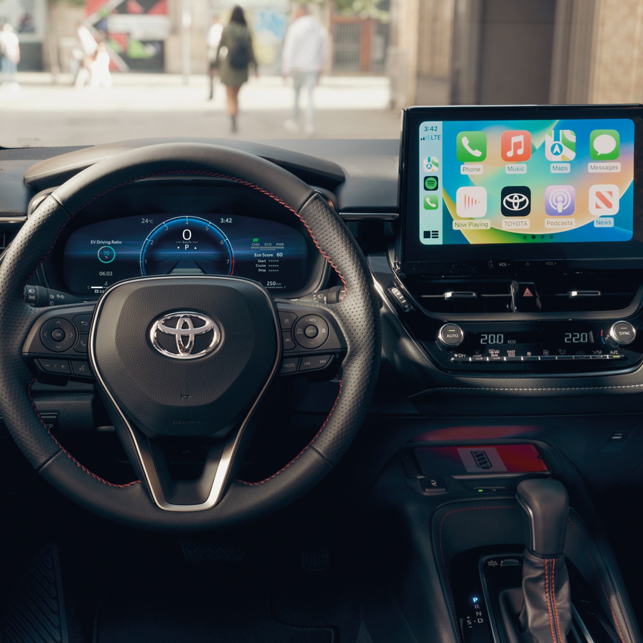 En multimedia-berøringsskjerm viser Apple CarPlay-hjemmeskjermen inne i en Toyota-bil med et svart dashbord.