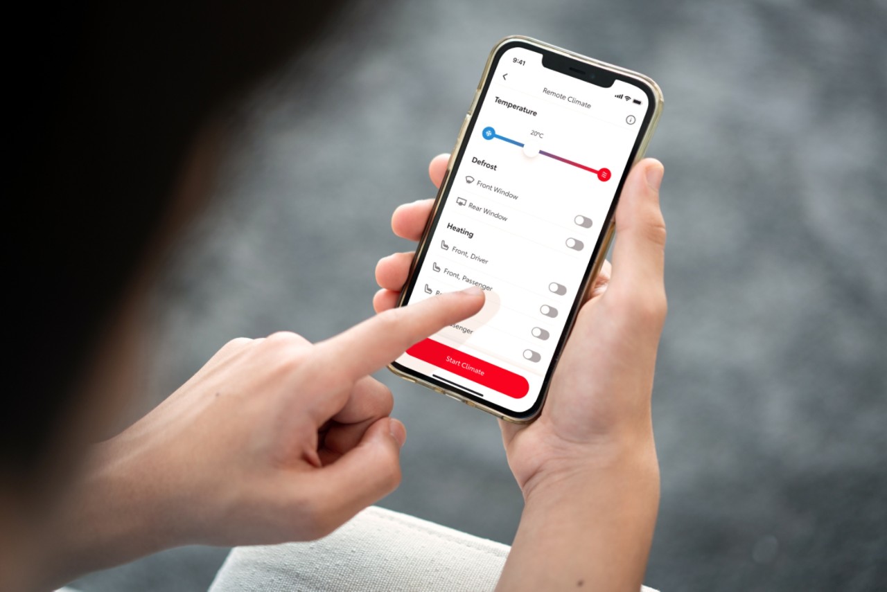En person holder en smarttelefon som viser MyToyota-appen. Venstrehånden deres trykker på skjermen for å forhåndsinnstille bilens klimaanlegg eksternt.
